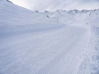 snow covered slope in the middle of a ski area as people ski on it near ski lift