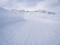 snow covered slope in the middle of a ski area as people ski on it near ski lift