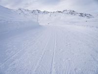 snow covered slope in the middle of a ski area as people ski on it near ski lift