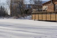 a building and fence covered in snow next to a street side walk and several tall buildings