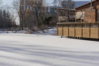 a building and fence covered in snow next to a street side walk and several tall buildings