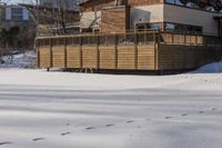 a building and fence covered in snow next to a street side walk and several tall buildings