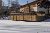 a building and fence covered in snow next to a street side walk and several tall buildings