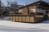 a building and fence covered in snow next to a street side walk and several tall buildings