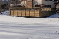 a building and fence covered in snow next to a street side walk and several tall buildings