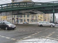 cars drive past a pedestrian bridge with traffic underneath it in wintertime - like conditions