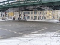 a pedestrian crossing over a snow covered street while someone crosses the road underneath it and cars driving under