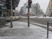 there is a light rail that has stopped on the street in the snow and people are crossing the tracks