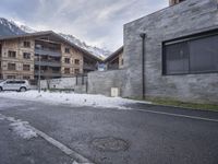 an old street in the mountains with cars parked in it under snow and some buildings