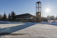 a church with snow on the ground and a big clock tower standing in front of it