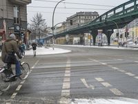 a man is riding a bike across the street on a snowy day wearing winter clothing