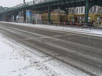 there is a man riding a bike down the road under a bridge in heavy snow