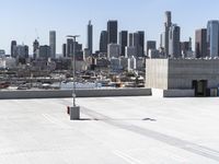 a man with black jacket skateboarding on cement outside of a building with city skyline in background