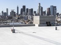 a man with black jacket skateboarding on cement outside of a building with city skyline in background