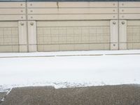 a parking meter sitting in the snow near buildings, looking toward the sidewalk area with trees