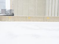 a parking meter sitting in the snow near buildings, looking toward the sidewalk area with trees