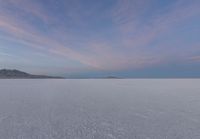 the snow is moving over the ground in the middle of the desert with mountain ranges