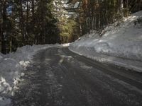 snow piled up on the side of a road next to a wooded area with trees in the background