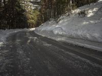 snow piled up on the side of a road next to a wooded area with trees in the background