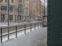 two people walking down a snowy path near buildings and a train track and the words on the sign are red