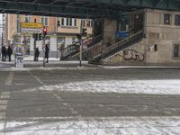 people walking in the snow and a building in the background with stairs in the street