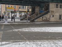 people walking in the snow and a building in the background with stairs in the street