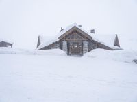 a snowboarder in front of a rustic log cabin in the mountains, in the foreground is a few snow