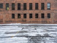 an old red brick building that has no windows and no fire hydrant or sidewalk