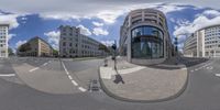 a panoramic view of a street with an intersection where traffic is stopped to pick up a car