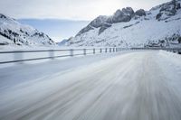 there is an extreme time exposure of snow traveling on this snowy road with mountains in the background