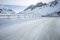 there is an extreme time exposure of snow traveling on this snowy road with mountains in the background