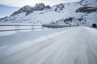 there is an extreme time exposure of snow traveling on this snowy road with mountains in the background