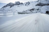 there is an extreme time exposure of snow traveling on this snowy road with mountains in the background
