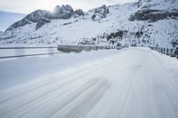 there is an extreme time exposure of snow traveling on this snowy road with mountains in the background