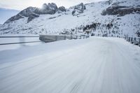 there is an extreme time exposure of snow traveling on this snowy road with mountains in the background