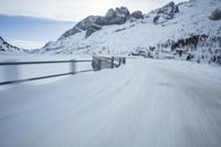 there is an extreme time exposure of snow traveling on this snowy road with mountains in the background