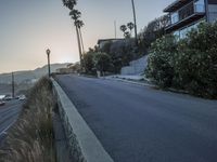 a street with cars driving down the road and hills in the background is a light house and blue ocean