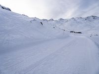 snow covered slope in the middle of a ski area as people ski on it near ski lift