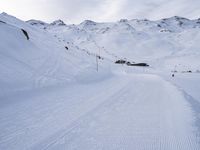 snow covered slope in the middle of a ski area as people ski on it near ski lift