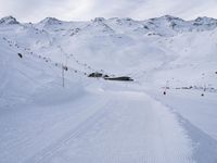 snow covered slope in the middle of a ski area as people ski on it near ski lift