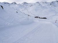 snow covered slope in the middle of a ski area as people ski on it near ski lift