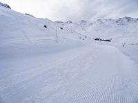 snow covered slope in the middle of a ski area as people ski on it near ski lift