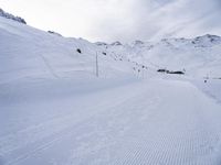 snow covered slope in the middle of a ski area as people ski on it near ski lift