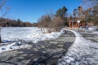 a walkway in the snow on a clear day with trees in the background and snow piled to the ground