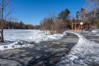 a walkway in the snow on a clear day with trees in the background and snow piled to the ground