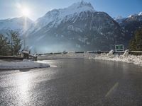 a black snow covered road in the mountains in the snow, as if for driving down a mountain