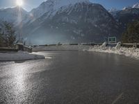 a black snow covered road in the mountains in the snow, as if for driving down a mountain