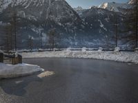 a black snow covered road in the mountains in the snow, as if for driving down a mountain