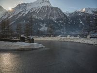 a black snow covered road in the mountains in the snow, as if for driving down a mountain