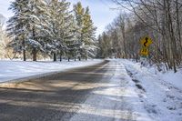 the sign reads turn right at the end of an empty road during wintertime in the canadian forest